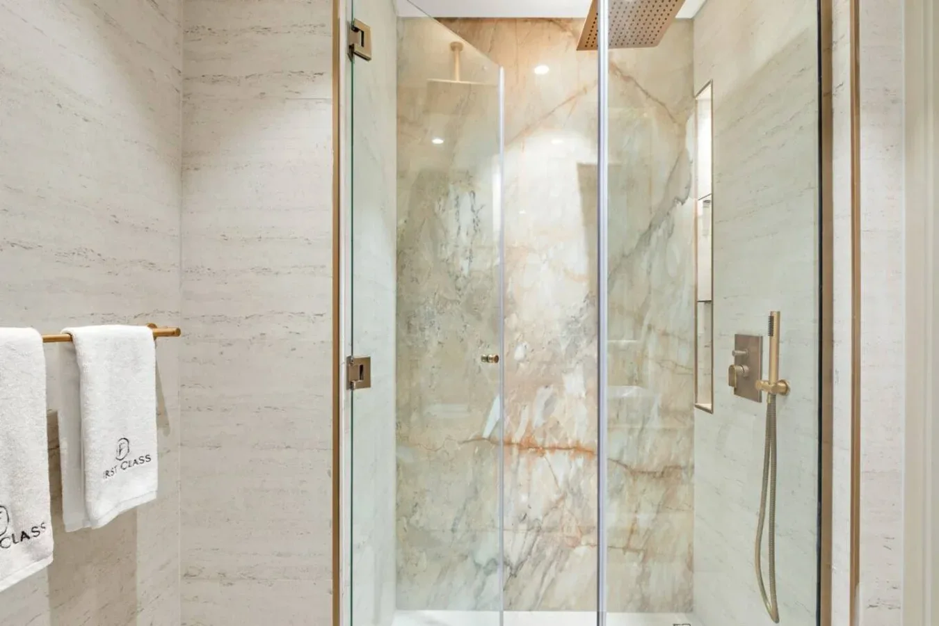 Una ducha de baño con paneles de vidrio transparente y un accesorio fijado a la pared.