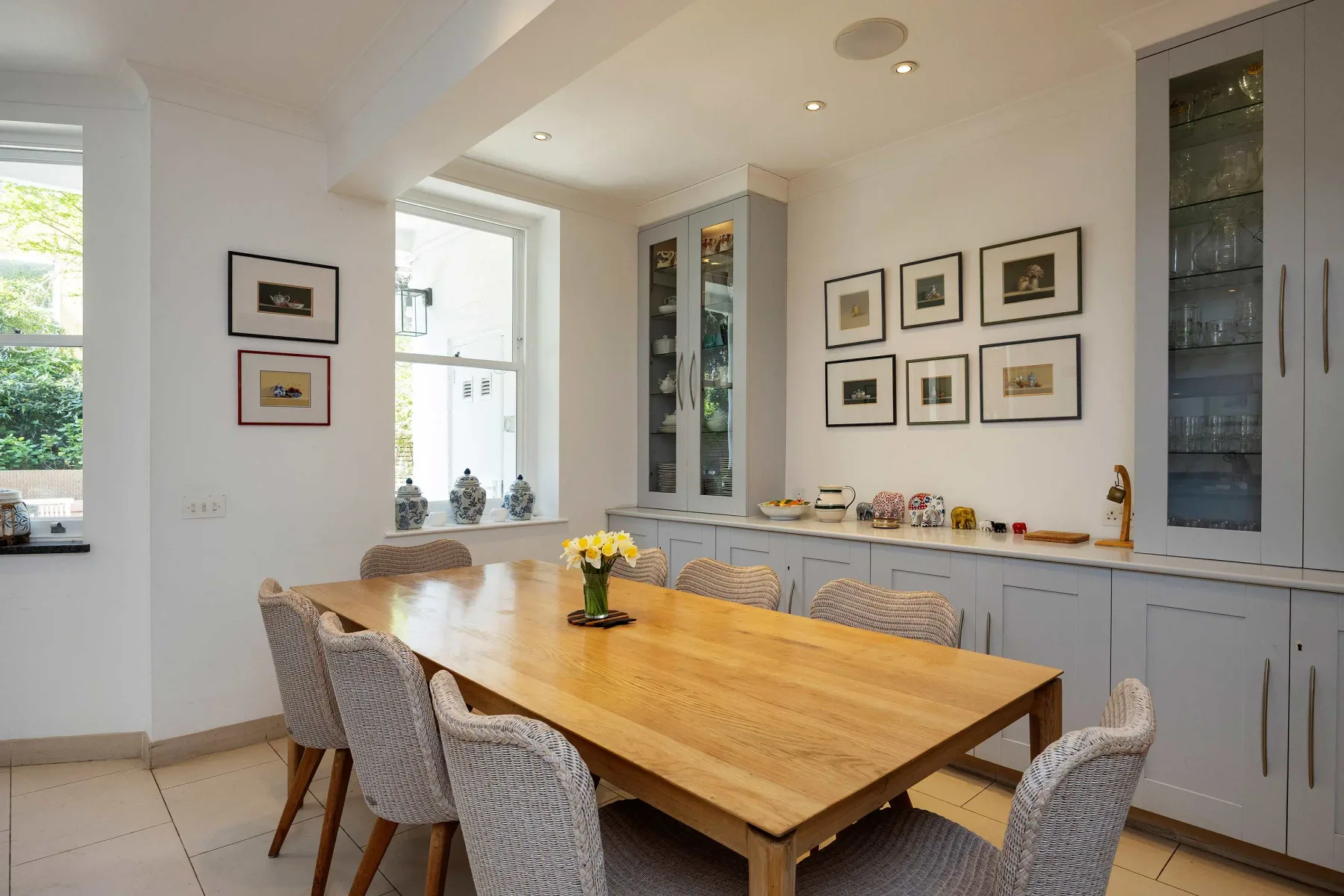 Un comedor luminoso con una mesa de madera y cuadros enmarcados.