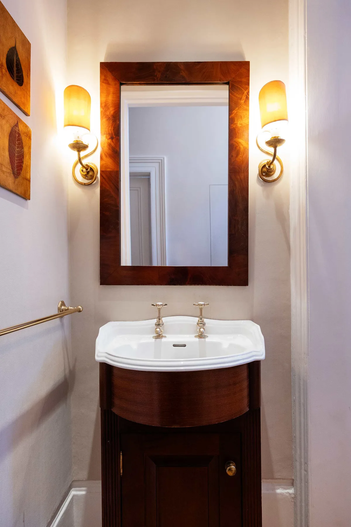 Un tocador de baño con lavabo blanco y un gran espejo enmarcado.