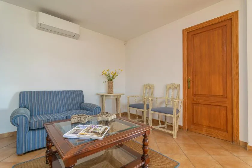 A sitting room with a blue striped sofa, a coffee table, and wooden door.