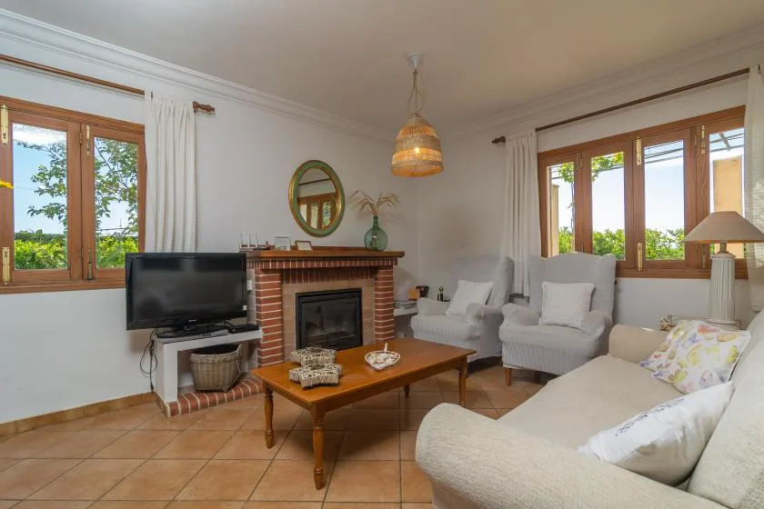 A living room with seating around a brick fireplace and wooden coffee table.