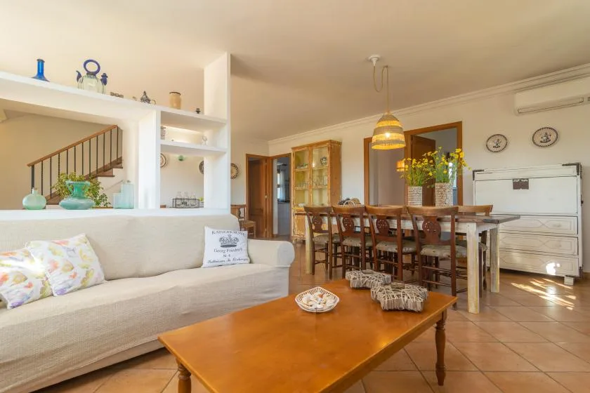 A living and dining area with a long table, seating, and a wooden coffee table.