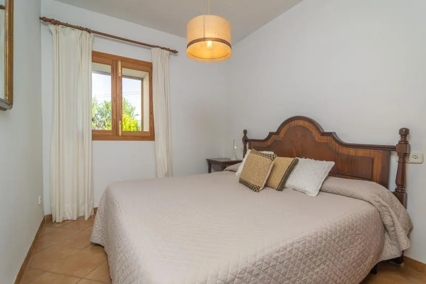 A bedroom with a large bed, decorative pillows, and a window with curtains.