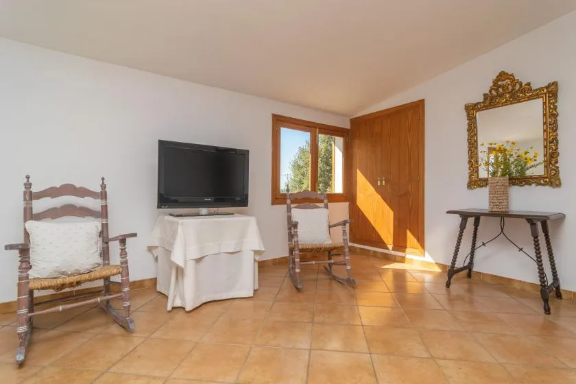 A bright room with seating, a television, and a sunlit wooden door.