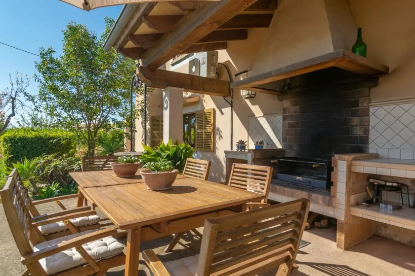 An outdoor dining area with a wooden table beside a built-in grill.