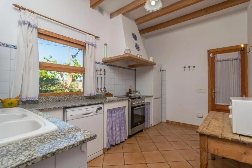 A tiled kitchen with a countertop, stove, and a window overlooking greenery.