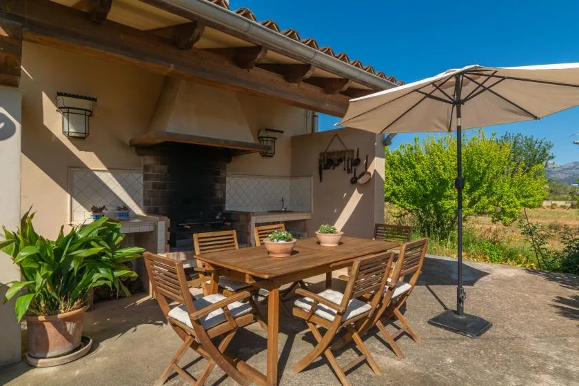 A covered outdoor dining area with a wooden table and a large patio umbrella.
