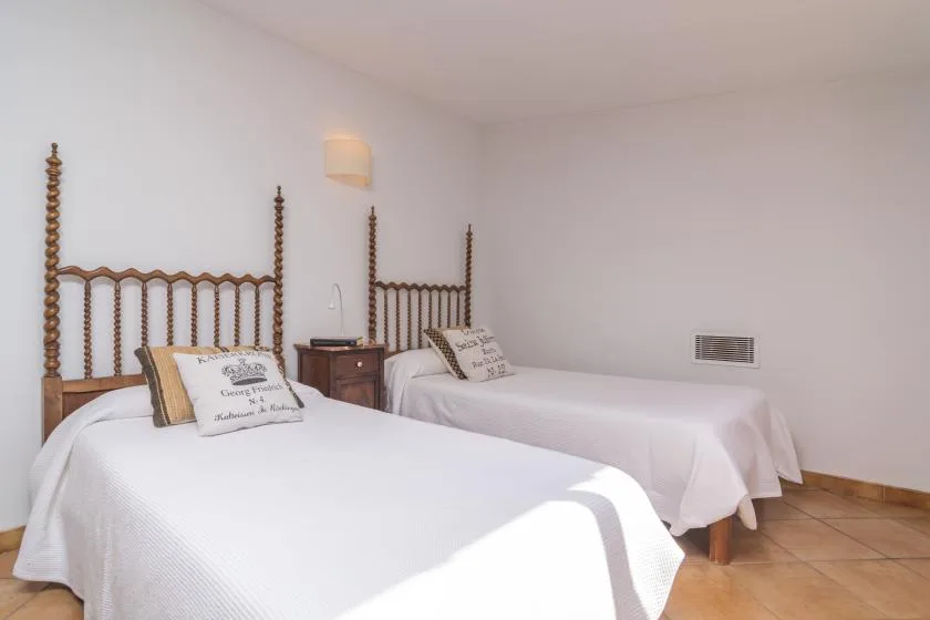 A bedroom with two beds, bedside tables, and white bedding.