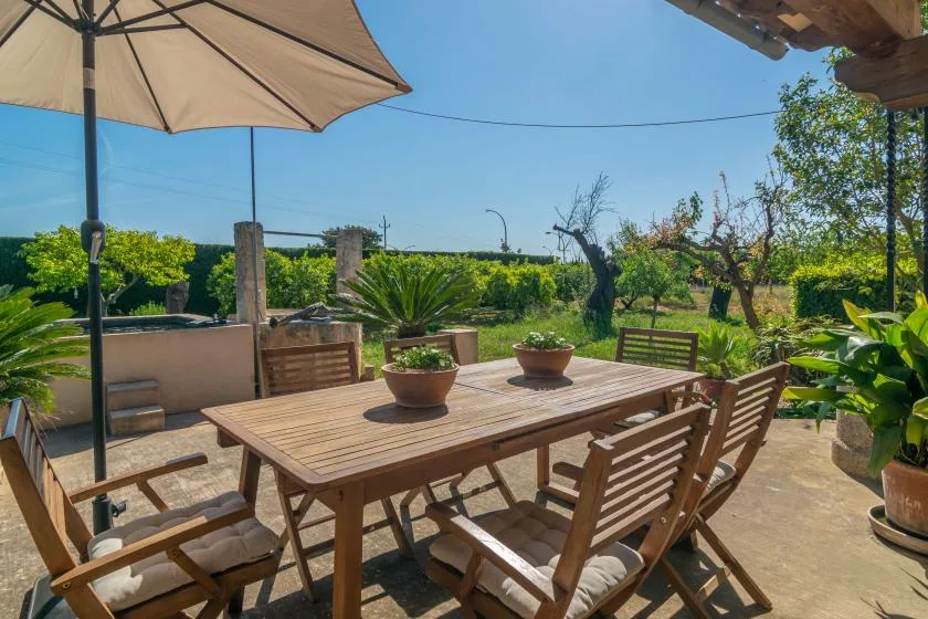 An outdoor dining area with a wooden table and seating overlooks a garden.