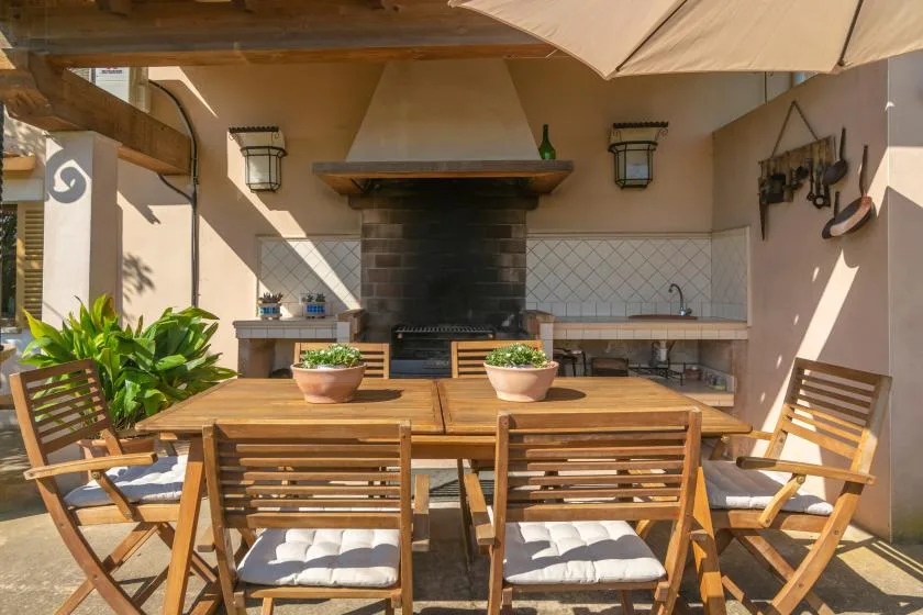 An outdoor dining area with a wooden table and a built-in grill.