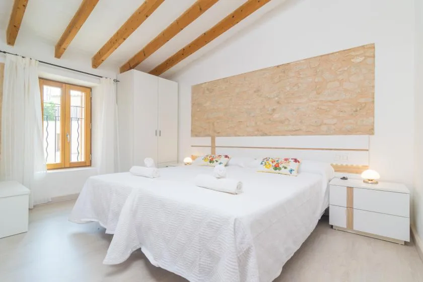 Un dormitorio luminoso con una cama grande bajo vigas de madera vistas.