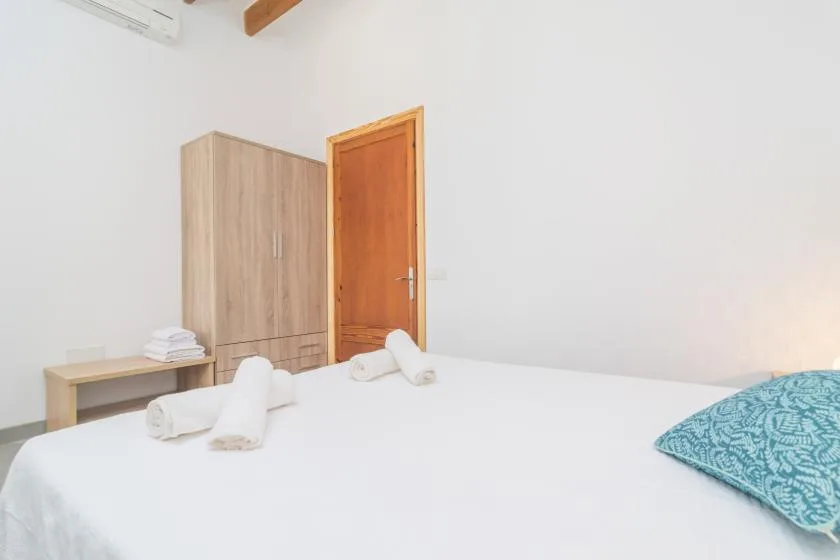 Un dormitorio con una cama bien tendida, toallas dobladas y un armario de madera.
