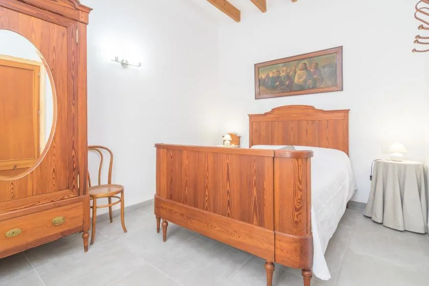 Un dormitorio con una cama de madera, un armario y una mesita auxiliar.