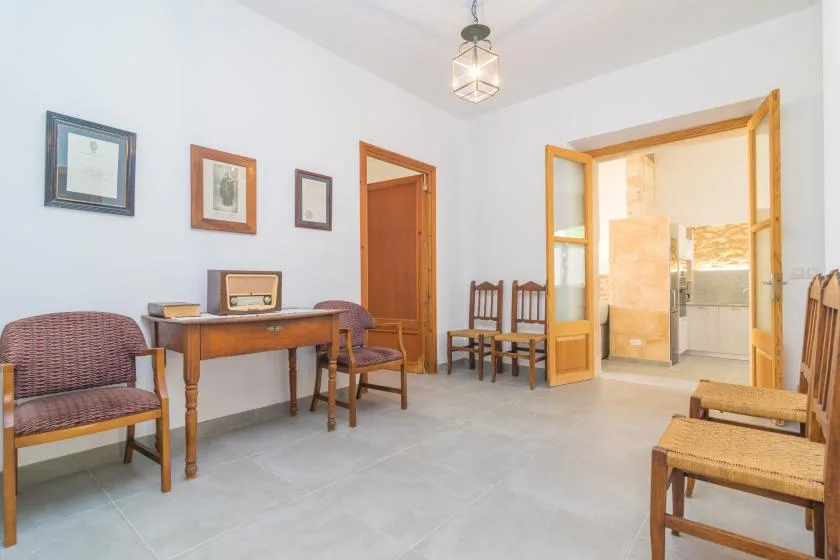 Una habitación luminosa con un escritorio de madera, sillas y una puerta abierta.