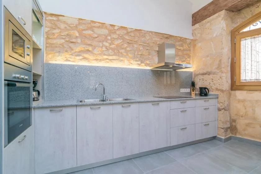 Una cocina con gabinetes claros, una encimera y una ventana.