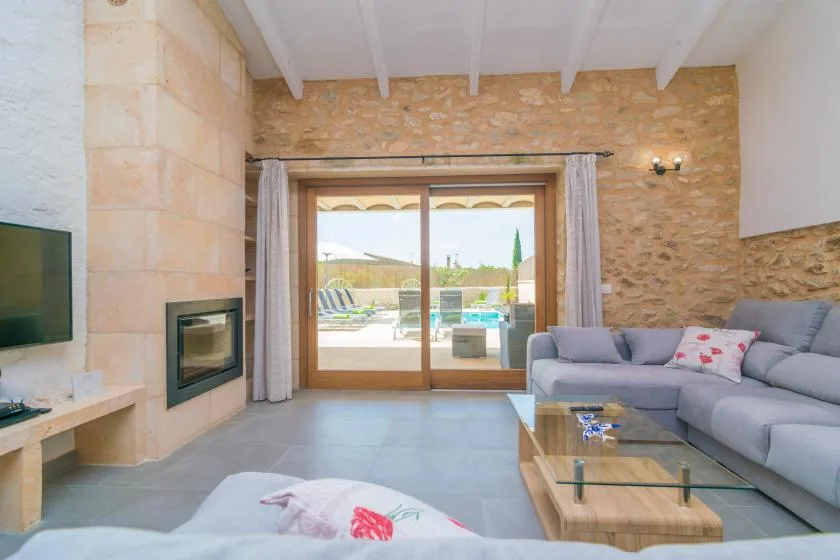 Una sala de estar con un sofá seccional gris y puertas corredizas de vidrio hacia un patio.
