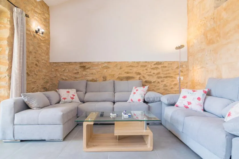 Una sala de estar con asientos grises dispuestos alrededor de una mesa de centro de vidrio.