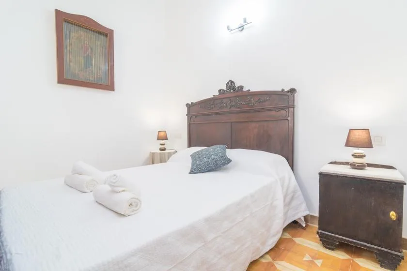 Un dormitorio con una cama vestida de blanco y un cabecero de madera oscura.