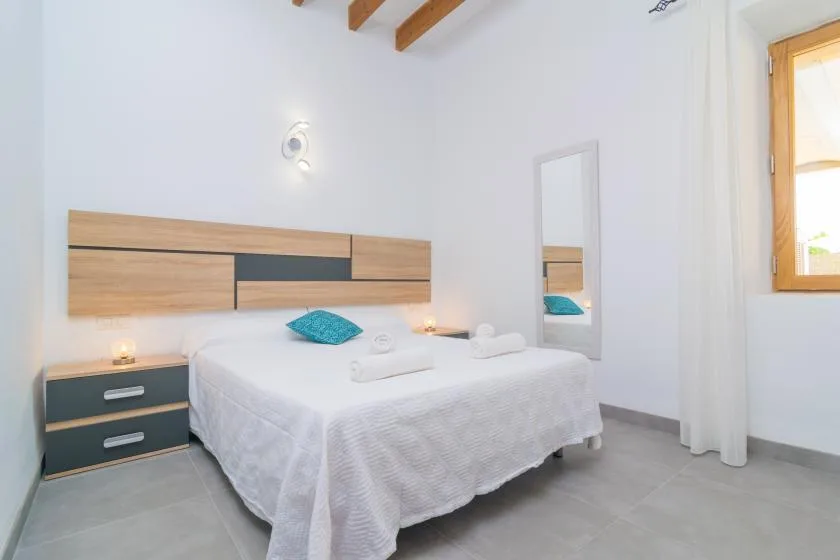 Un dormitorio luminoso con una cama doble, cabecero de madera y mesita de noche.