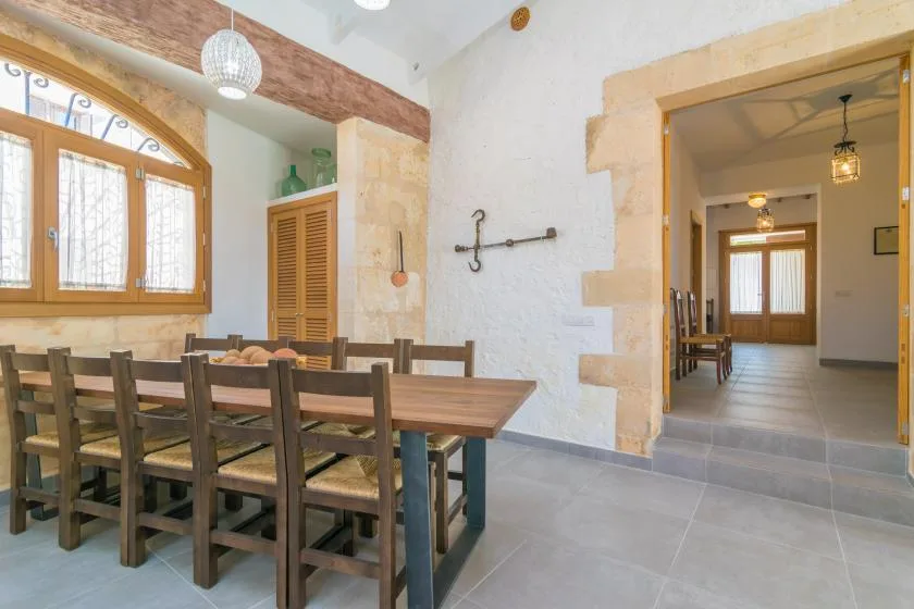 Comedor con una mesa larga de madera y sillas junto a una puerta abierta.