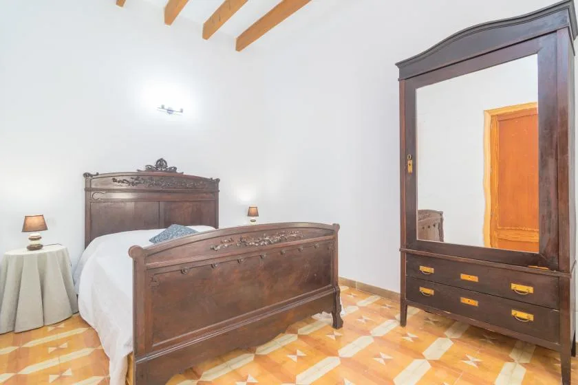 Un dormitorio con una cama de madera y un armario grande con espejo.