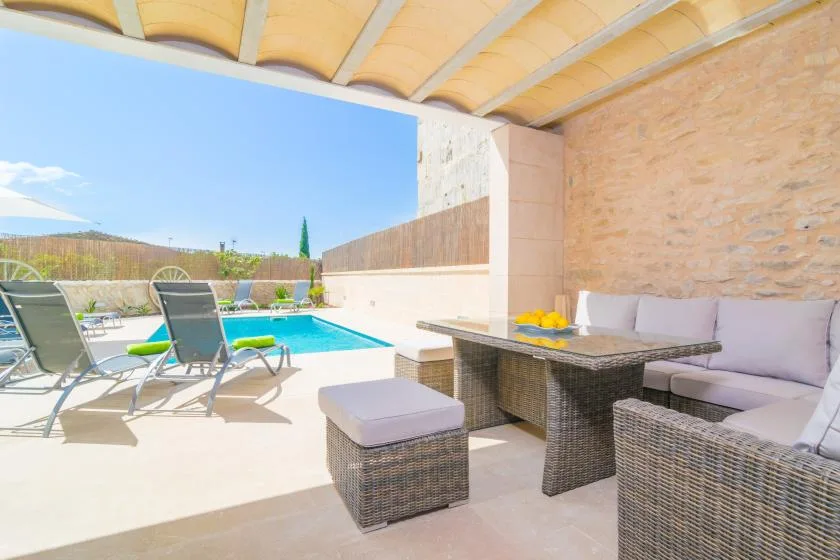 Una zona exterior cubierta con una mesa y asientos da a una piscina.