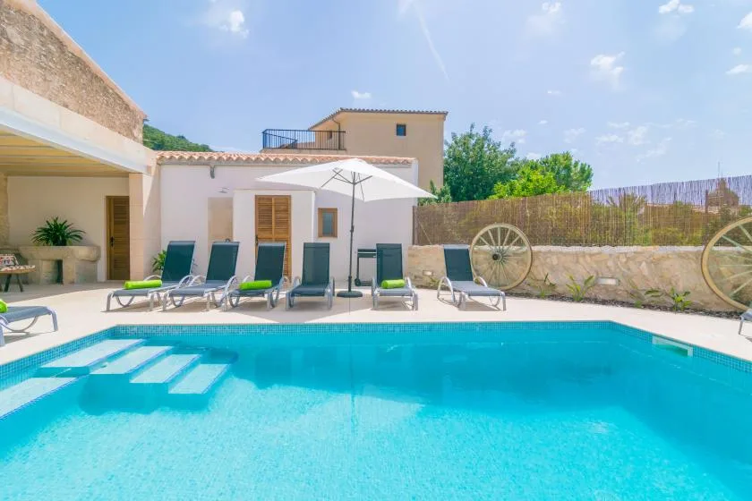 Una piscina y un patio con asientos junto a un edificio bajo de color claro.