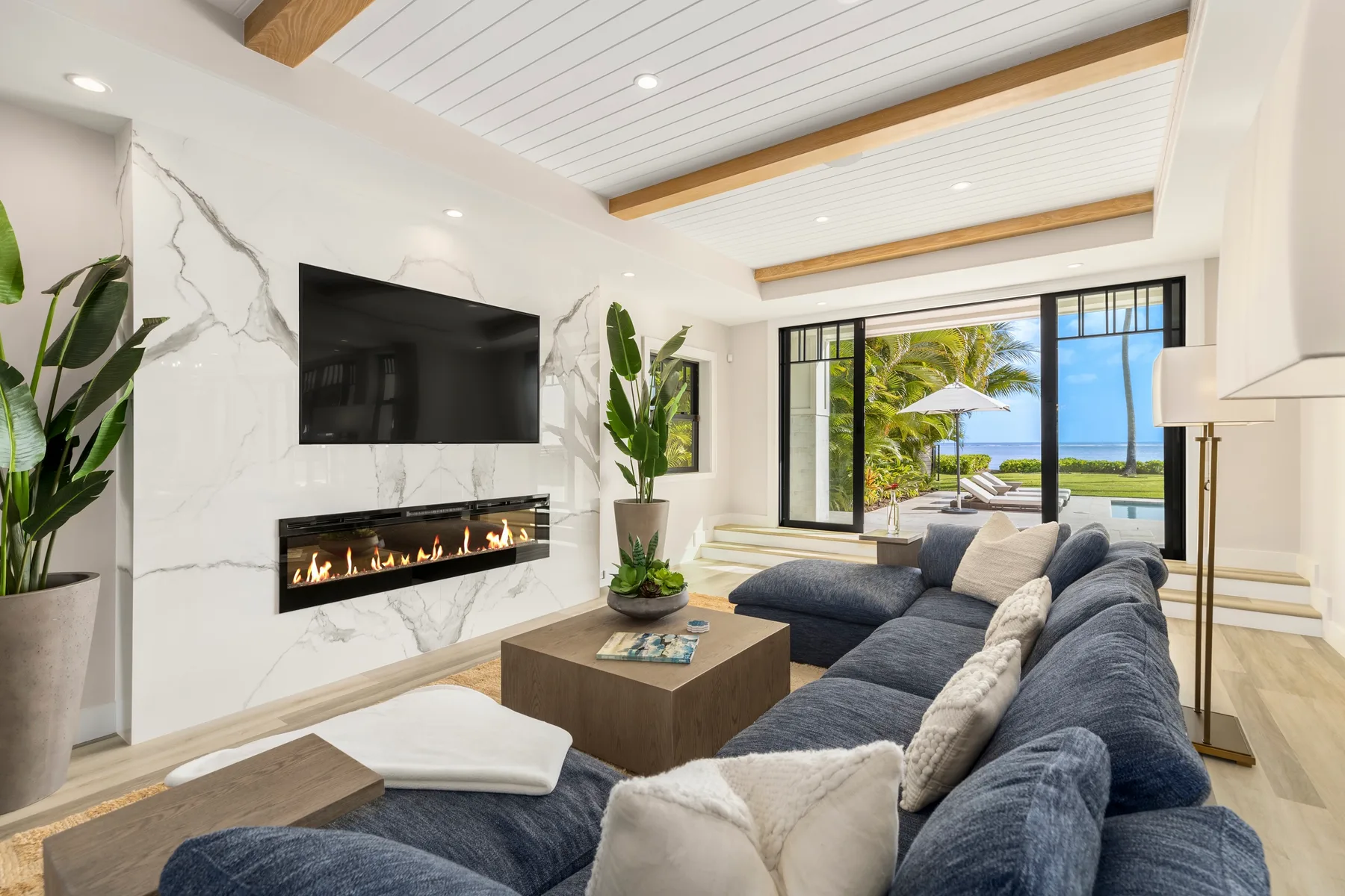 Una sala luminosa tiene un área de asientos frente a un televisor de pared y una chimenea.