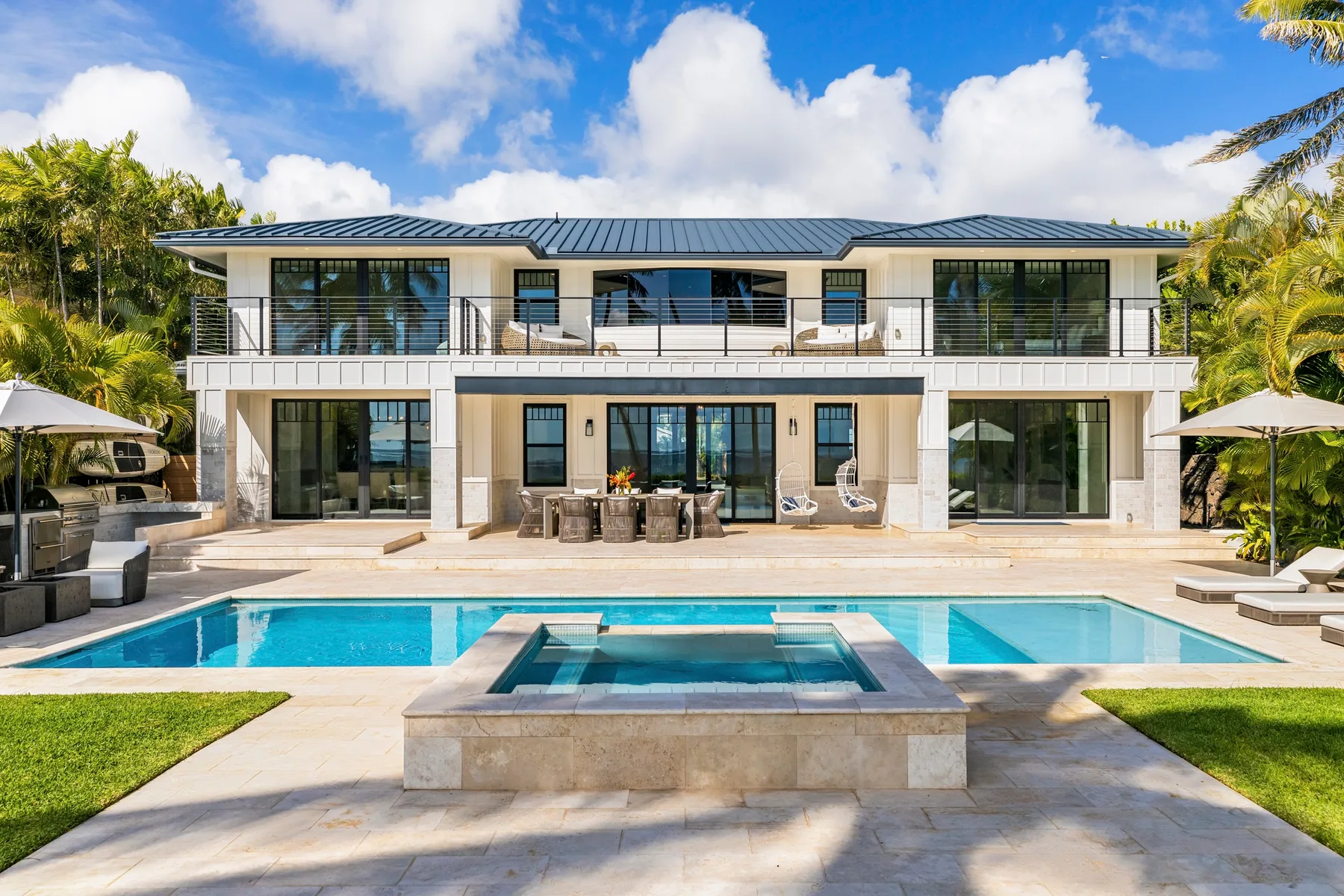 A modern two-story house overlooks a swimming pool and raised spa.