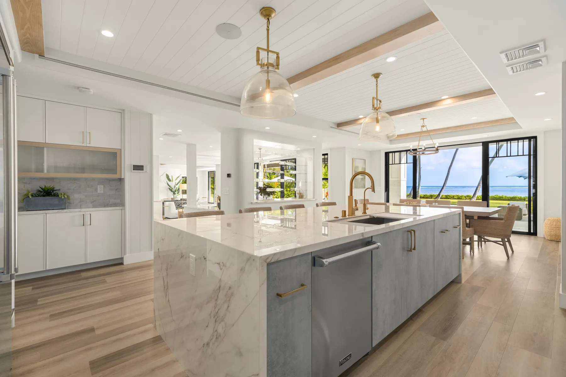Una cocina luminosa con una isla grande y comedor junto a amplios ventanales.
