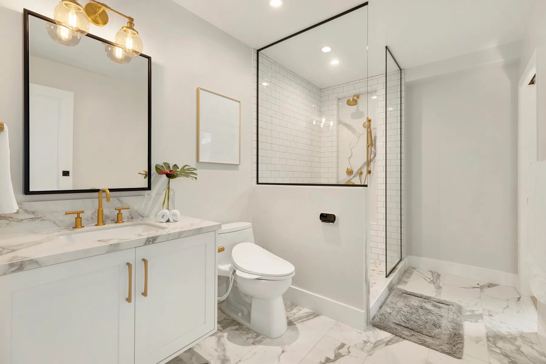 Un baño luminoso con lavabo, inodoro y ducha con mampara de vidrio.