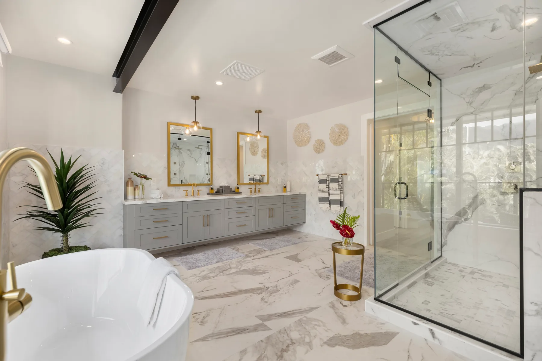 Un baño luminoso cuenta con bañera exenta, lavabo doble y ducha de vidrio.