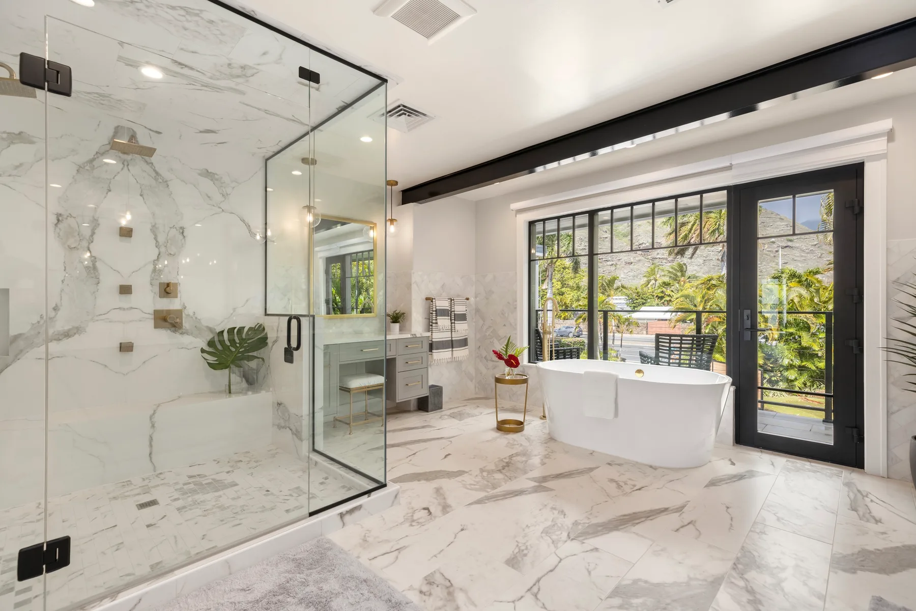 Un baño luminoso con una bañera exenta junto a grandes ventanas.