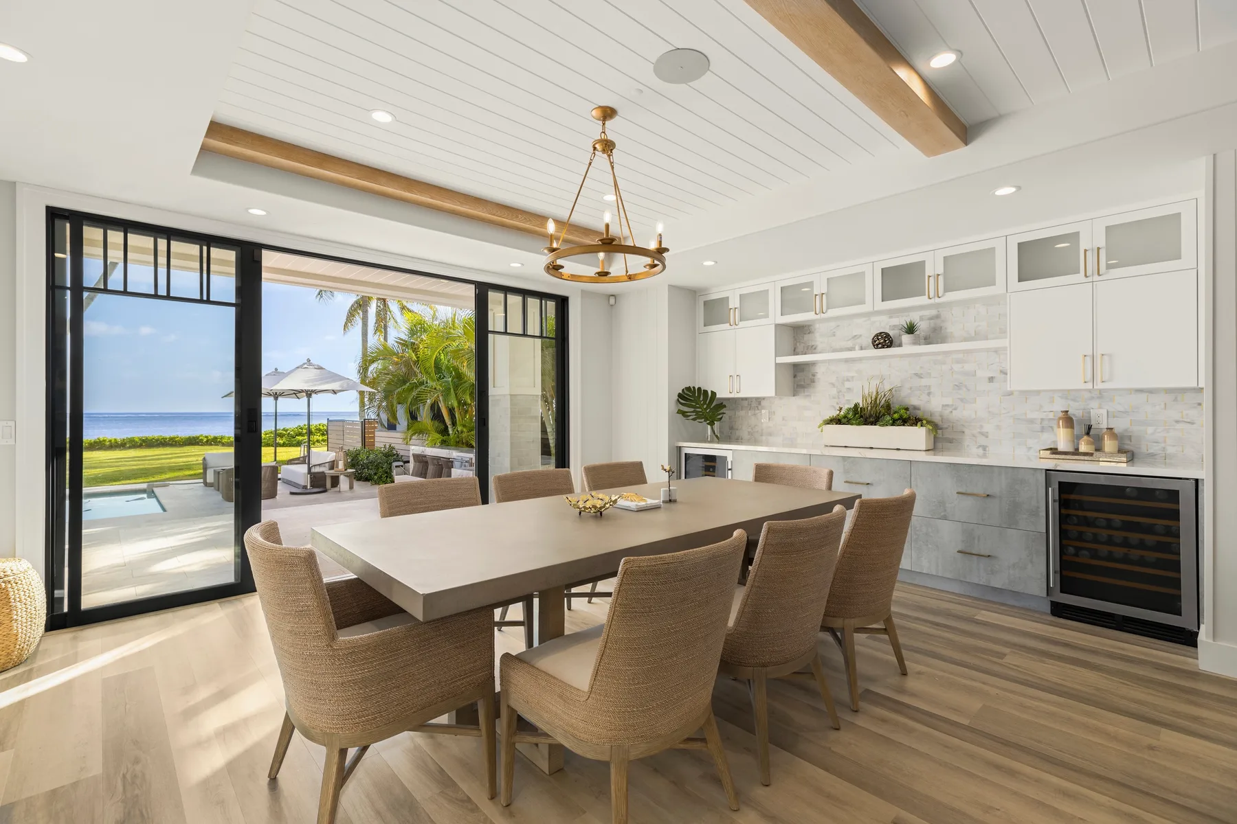 A dining area with a long table and seating beside large glass doors.