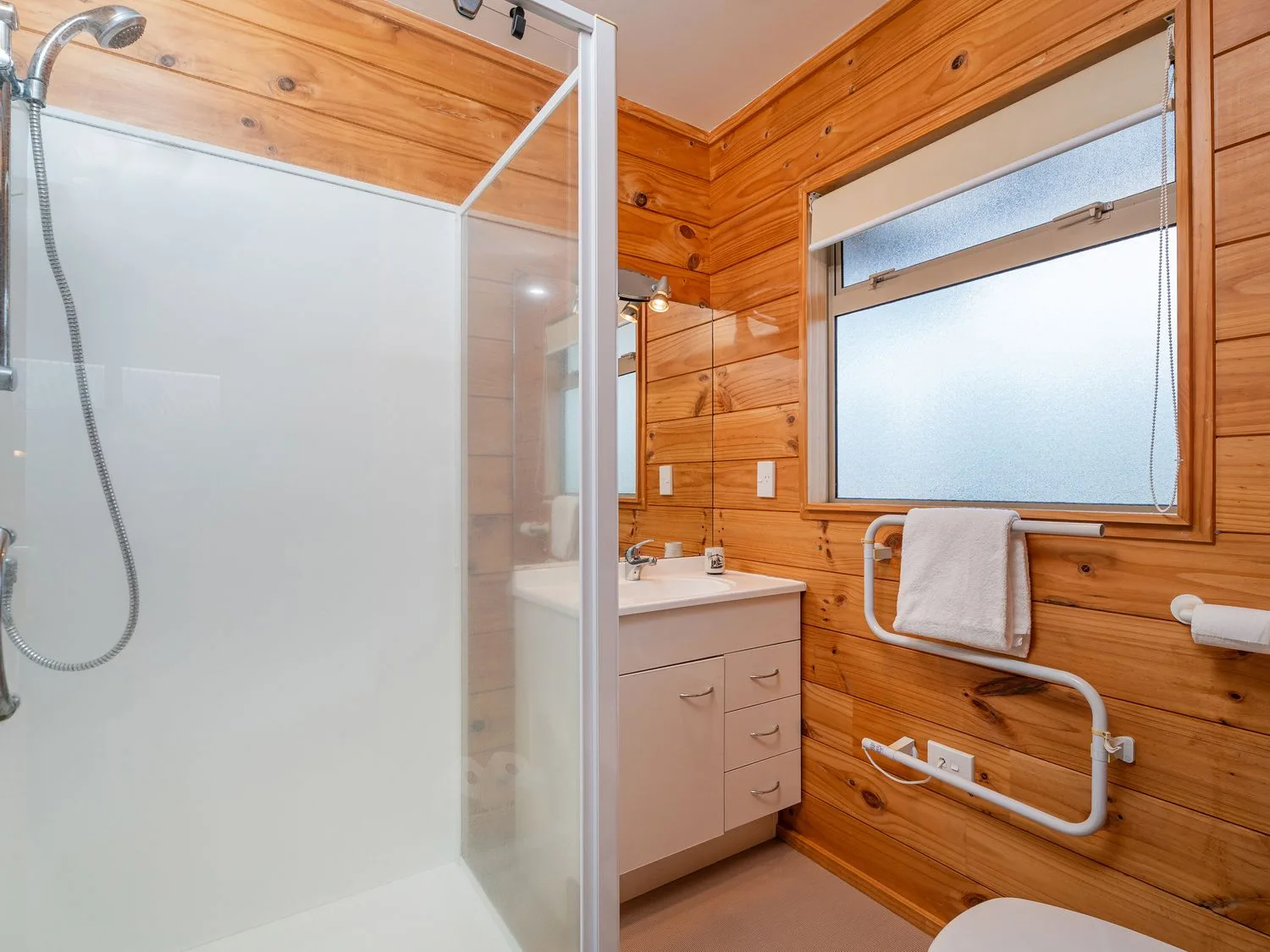 A bathroom with a shower, sink, and toilet at Whangapoua