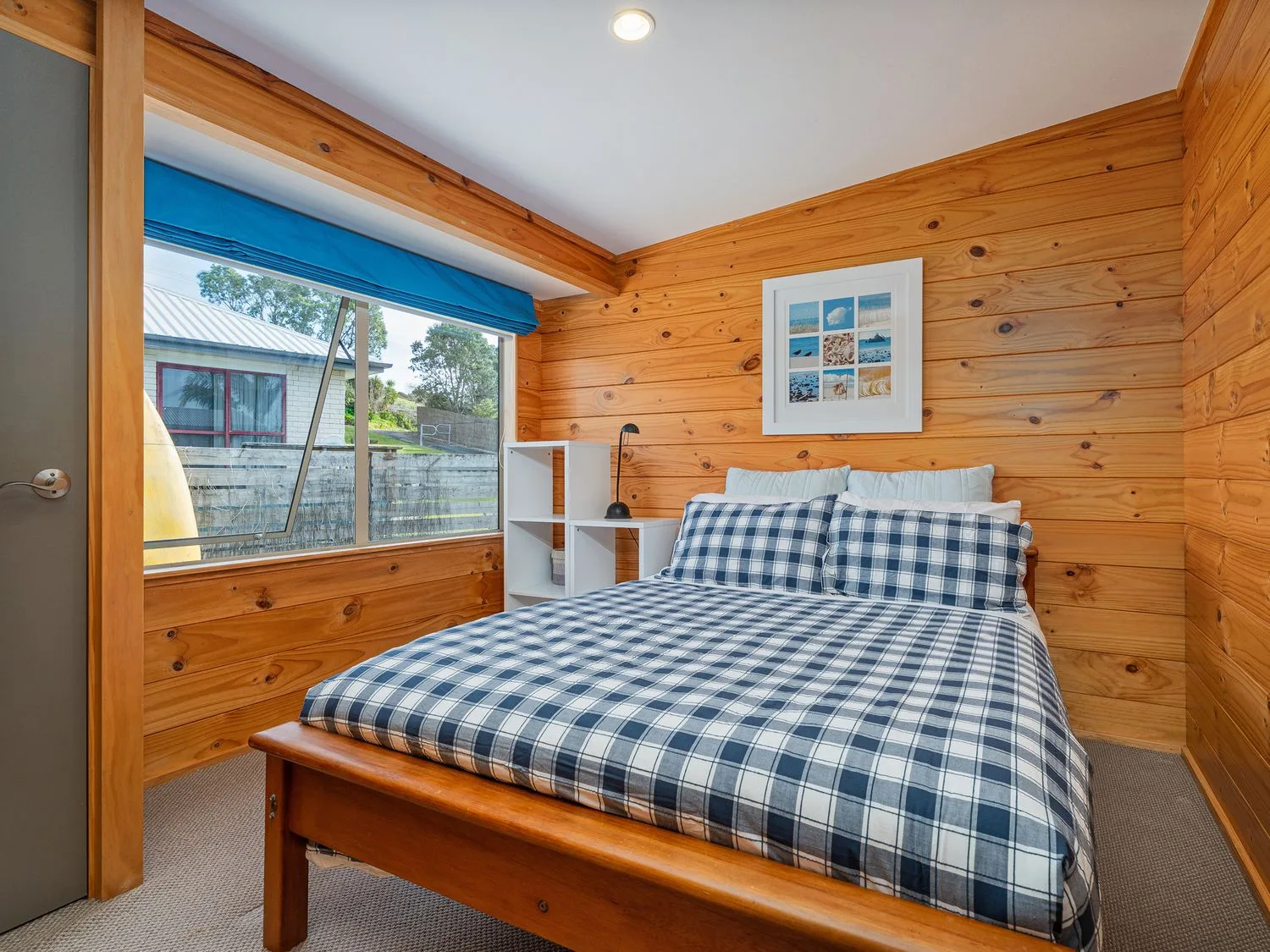 A bedroom with a wooden bed and blue-and-white checkered bedding.