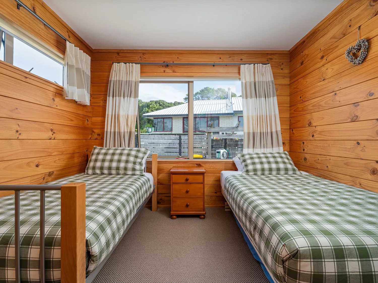 A bedroom with two beds and a side table at Whangapoua