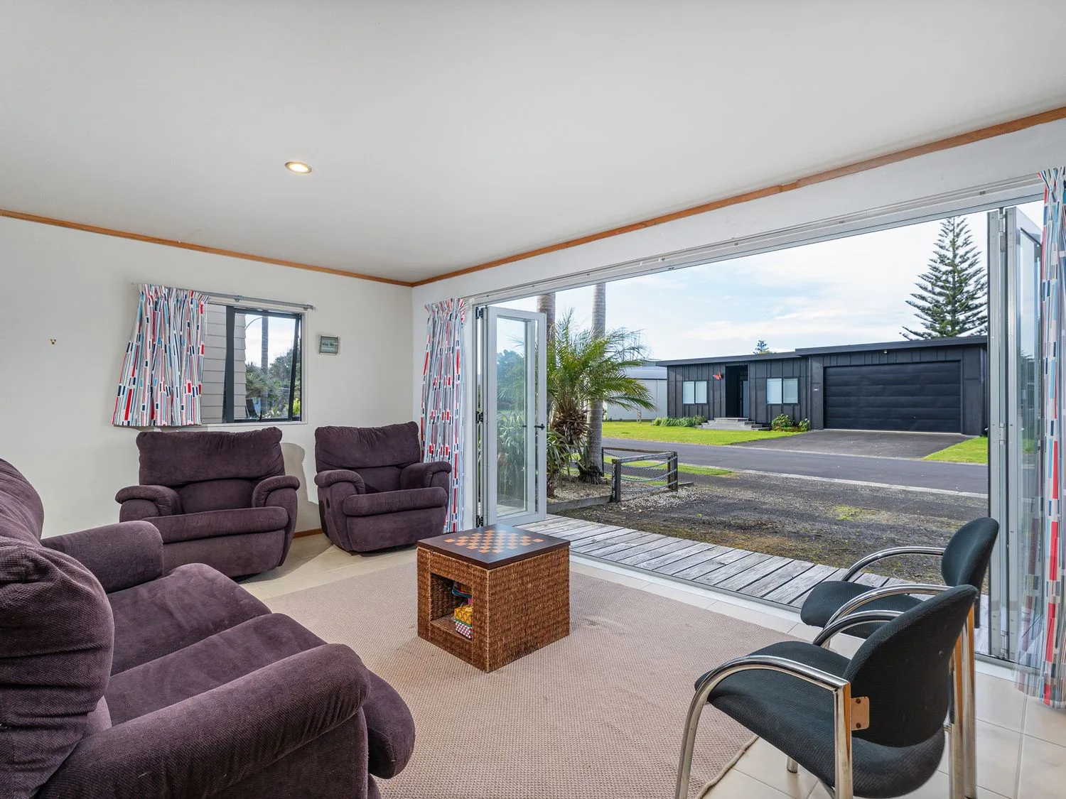 A living room with seating and a coffee table beside wide glass doors.