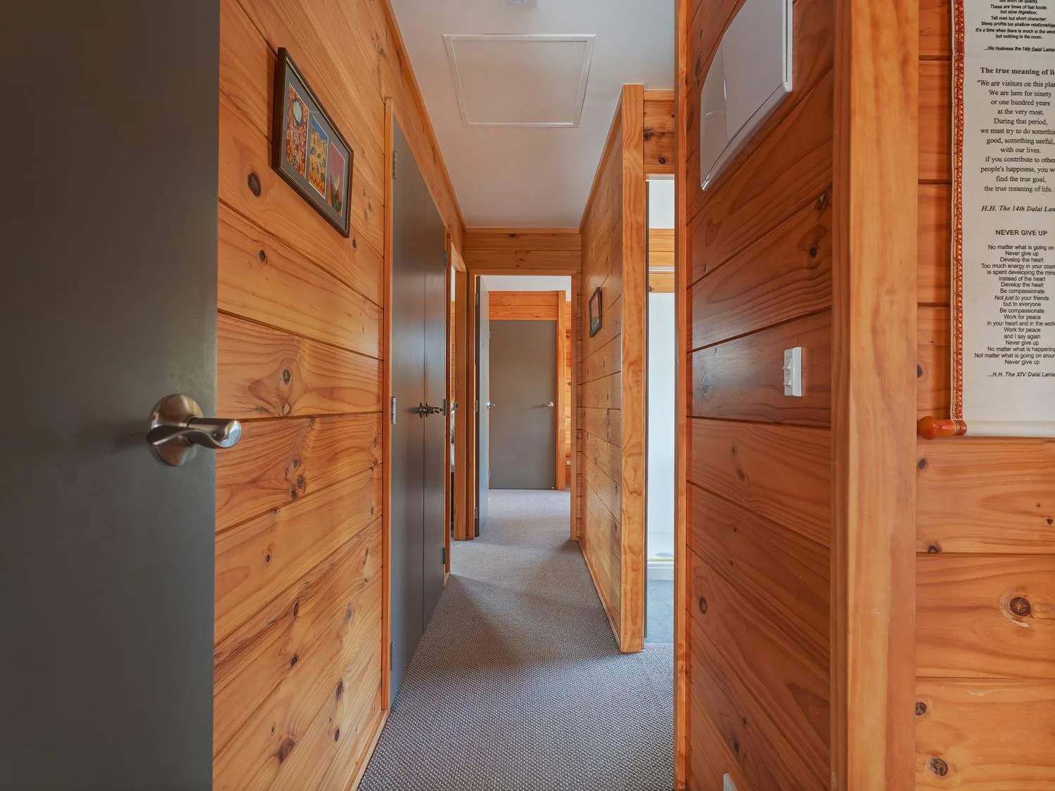 A hallway with wooden walls, several doors, and carpeted flooring.
