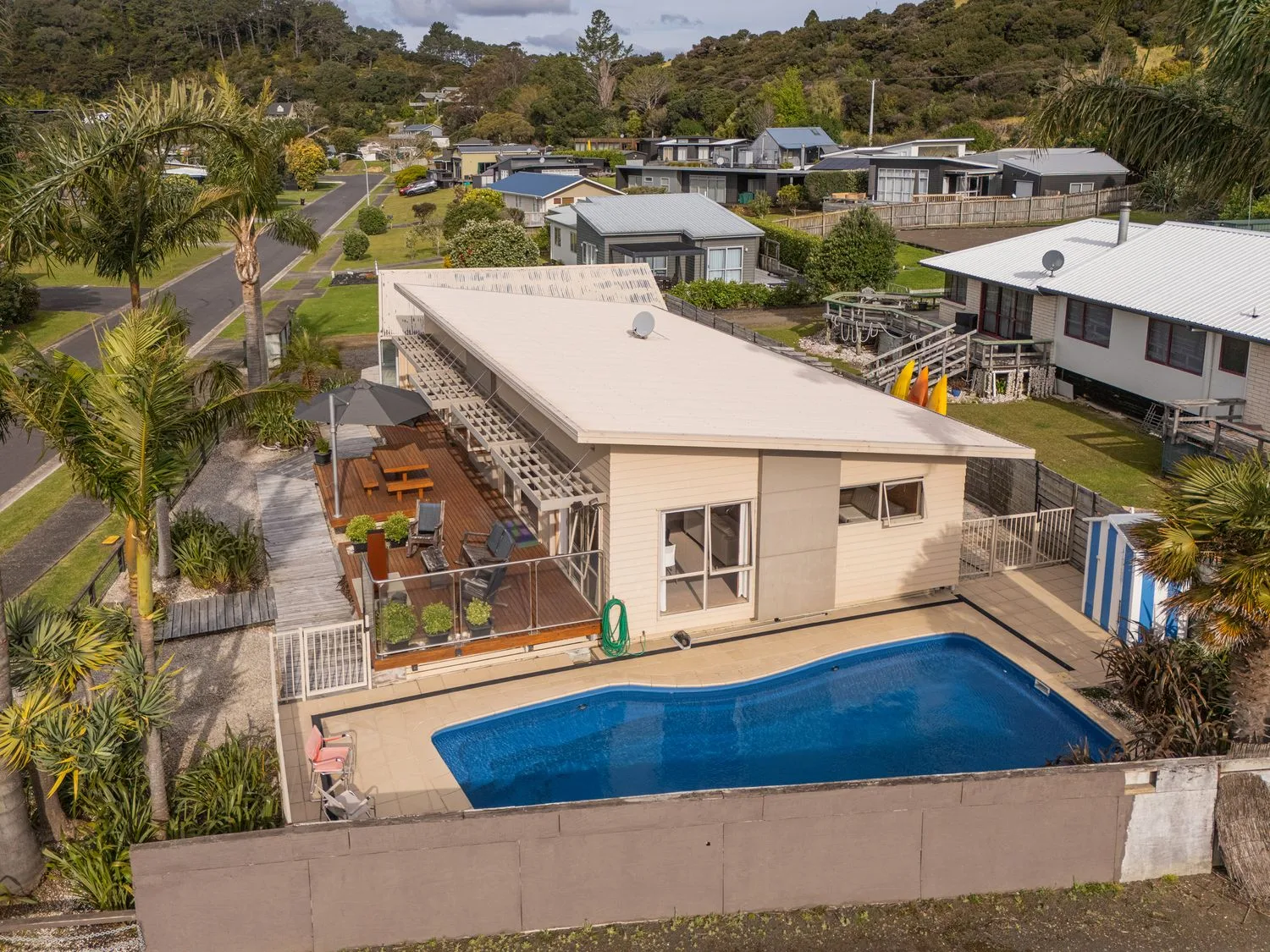 An outdoor swimming pool sits beside a low building and landscaped grounds.