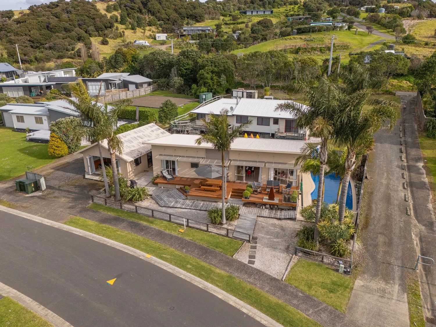 Aerial view of a single-story house with a fenced outdoor patio beside the road.