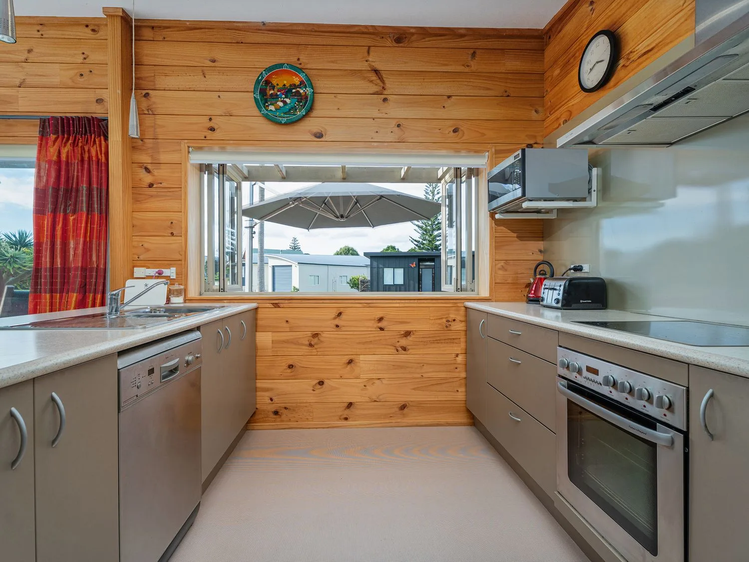 A kitchen with stainless steel appliances and a window at Whangapoua