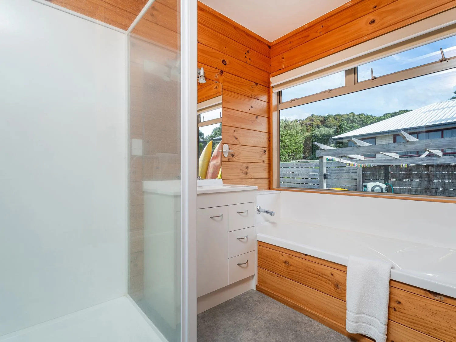 A bathroom with a shower and bathtub beside a large window.