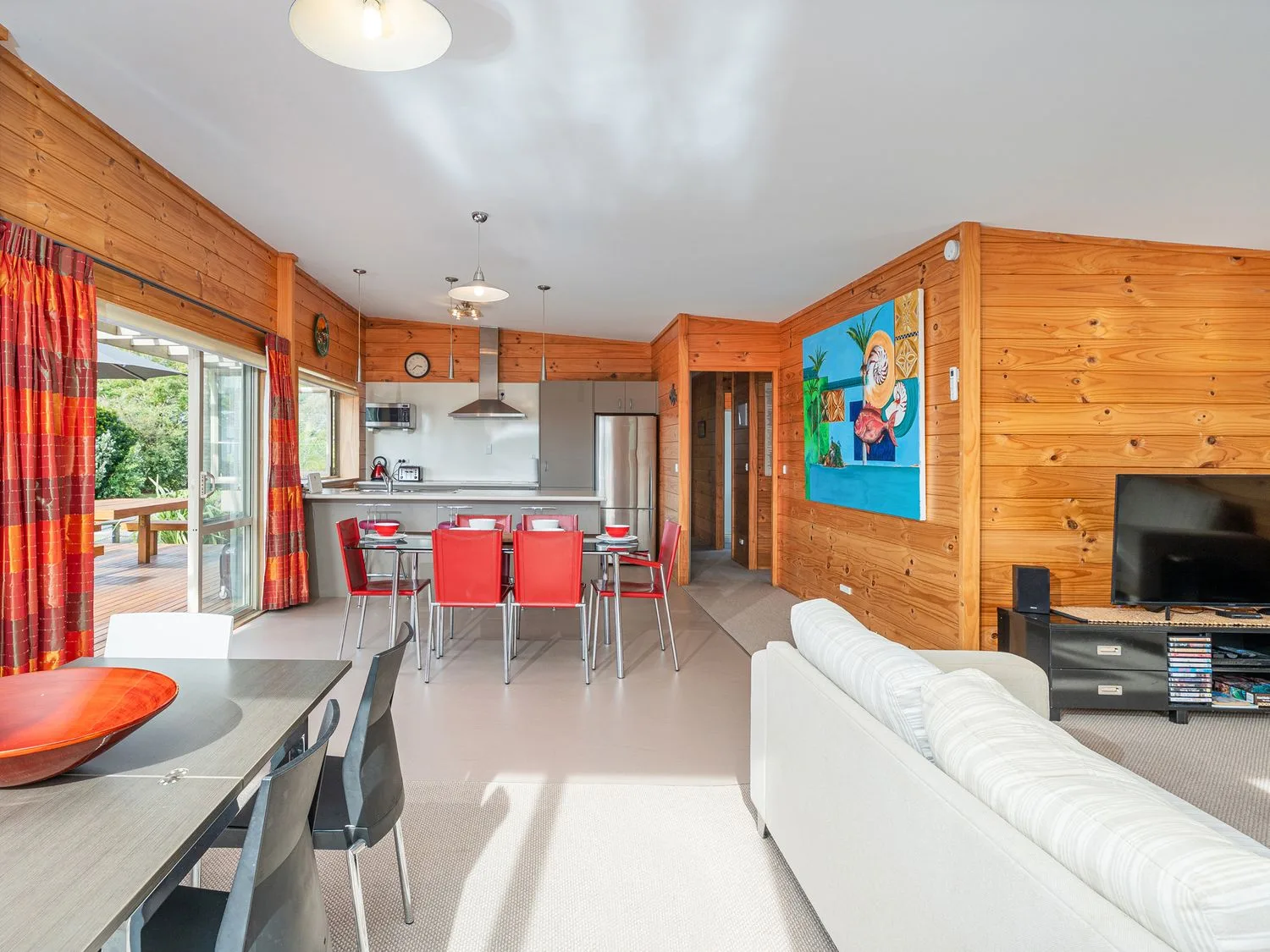 A wood-paneled living room opens into a dining area and kitchen.