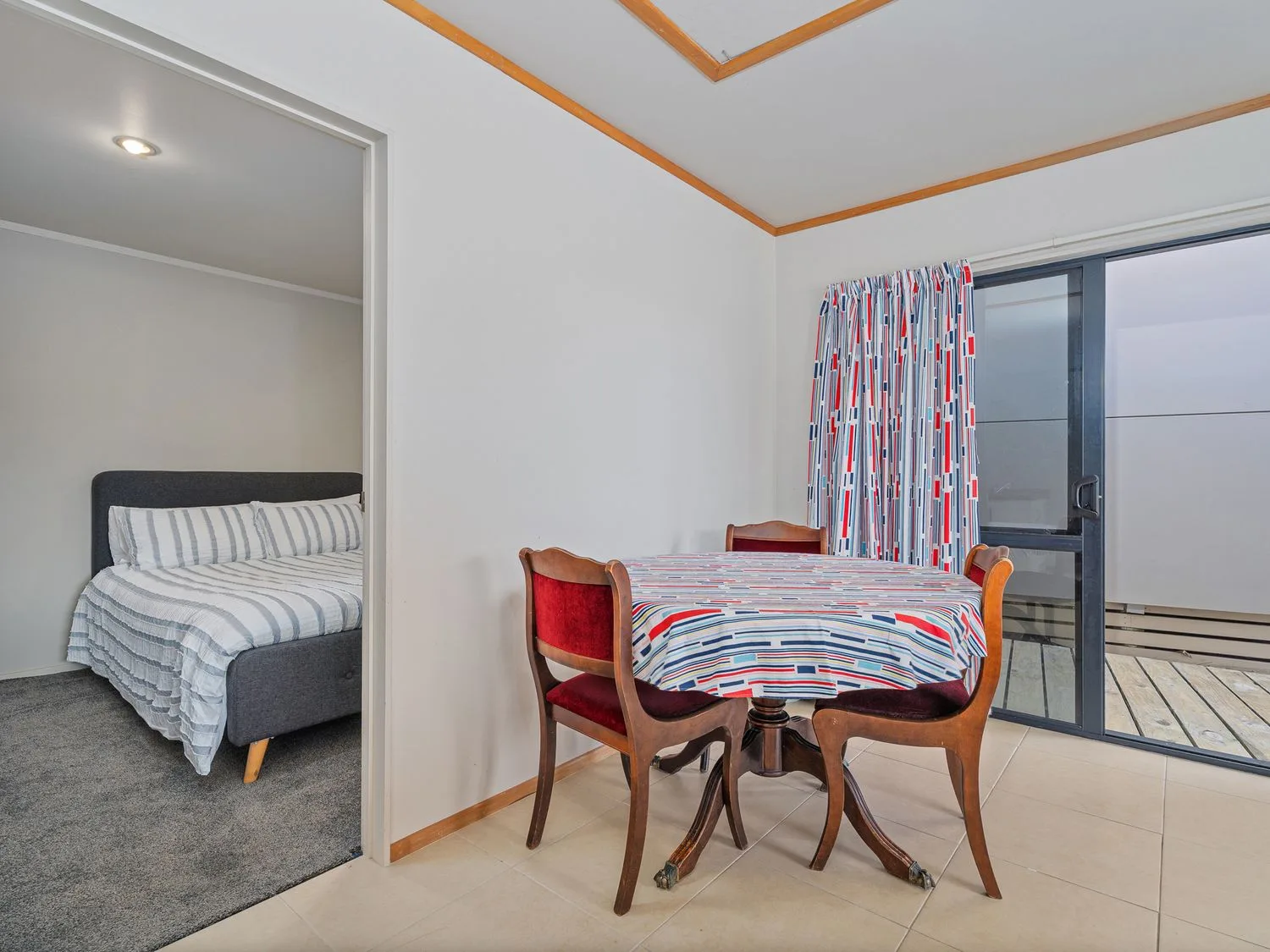 A dining area with a table and chairs sits beside a bedroom.