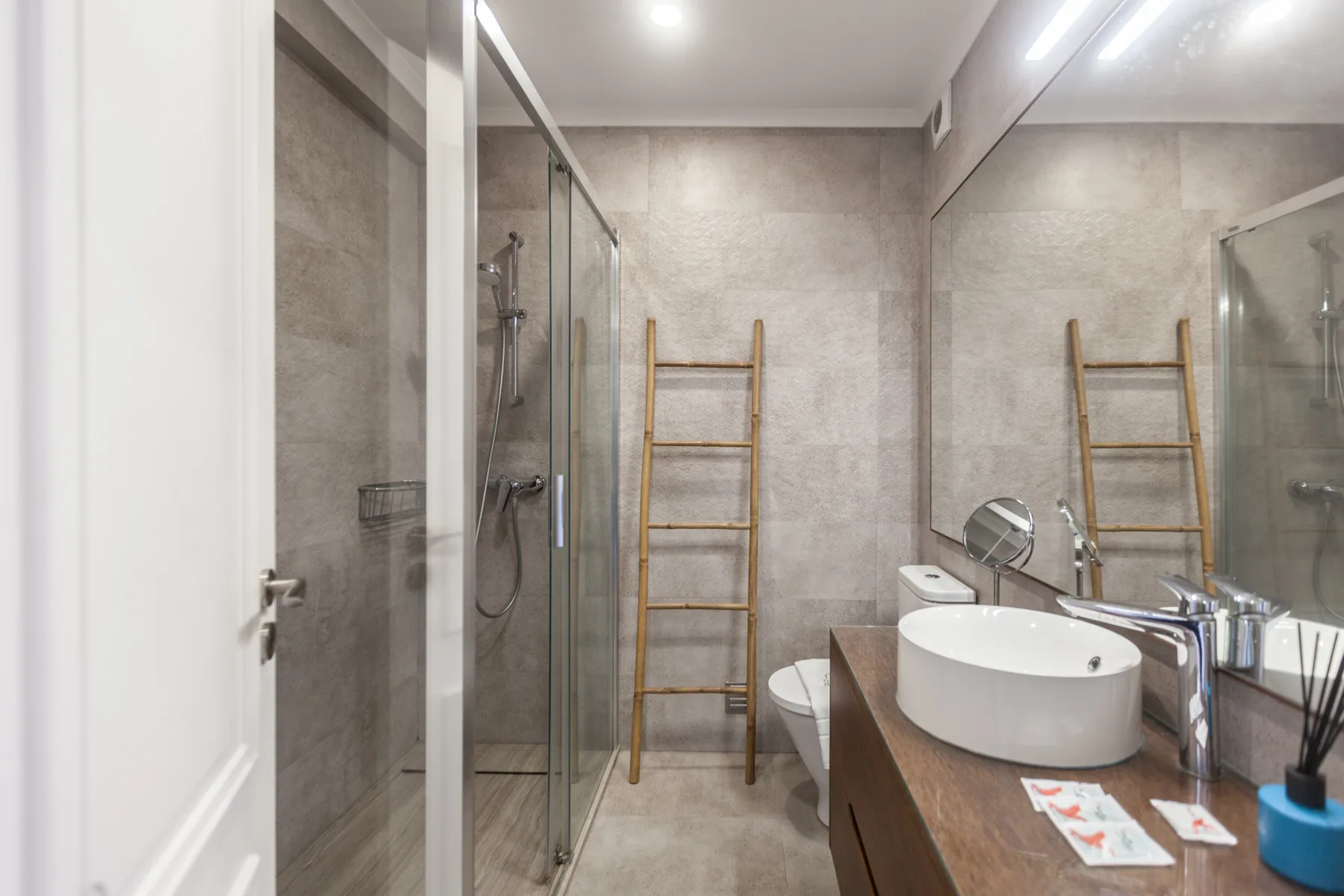 Un baño alicatado con una ducha de vidrio y un lavabo sobre la encimera.