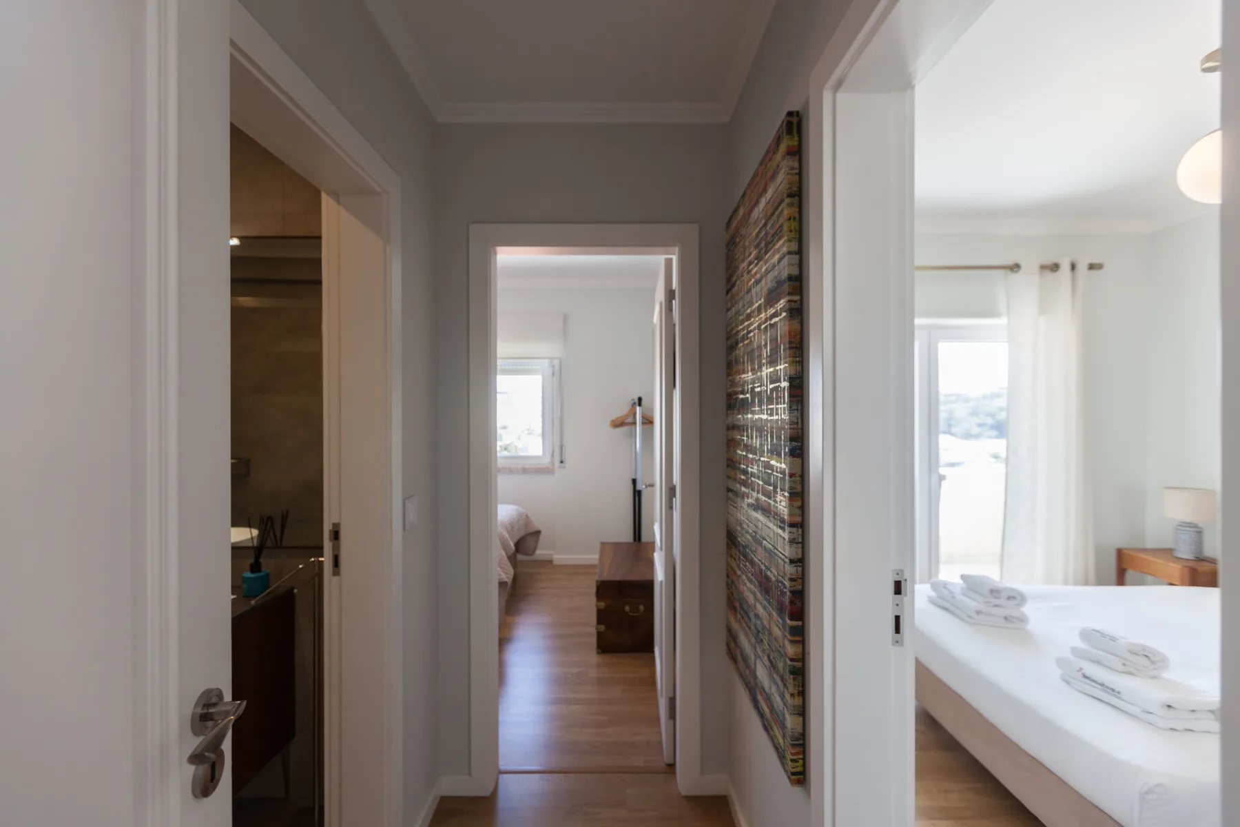 Un pasillo conecta el dormitorio y el baño, con una obra colorida en la pared.