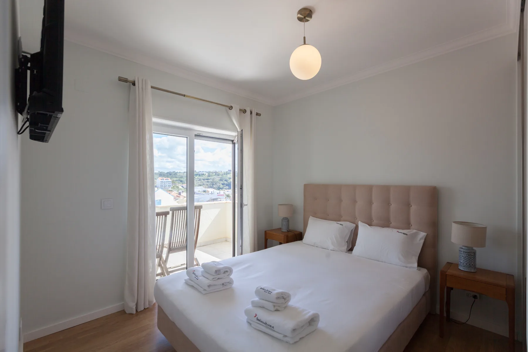 Un dormitorio con cama doble, mesillas de noche y una ventana luminosa.