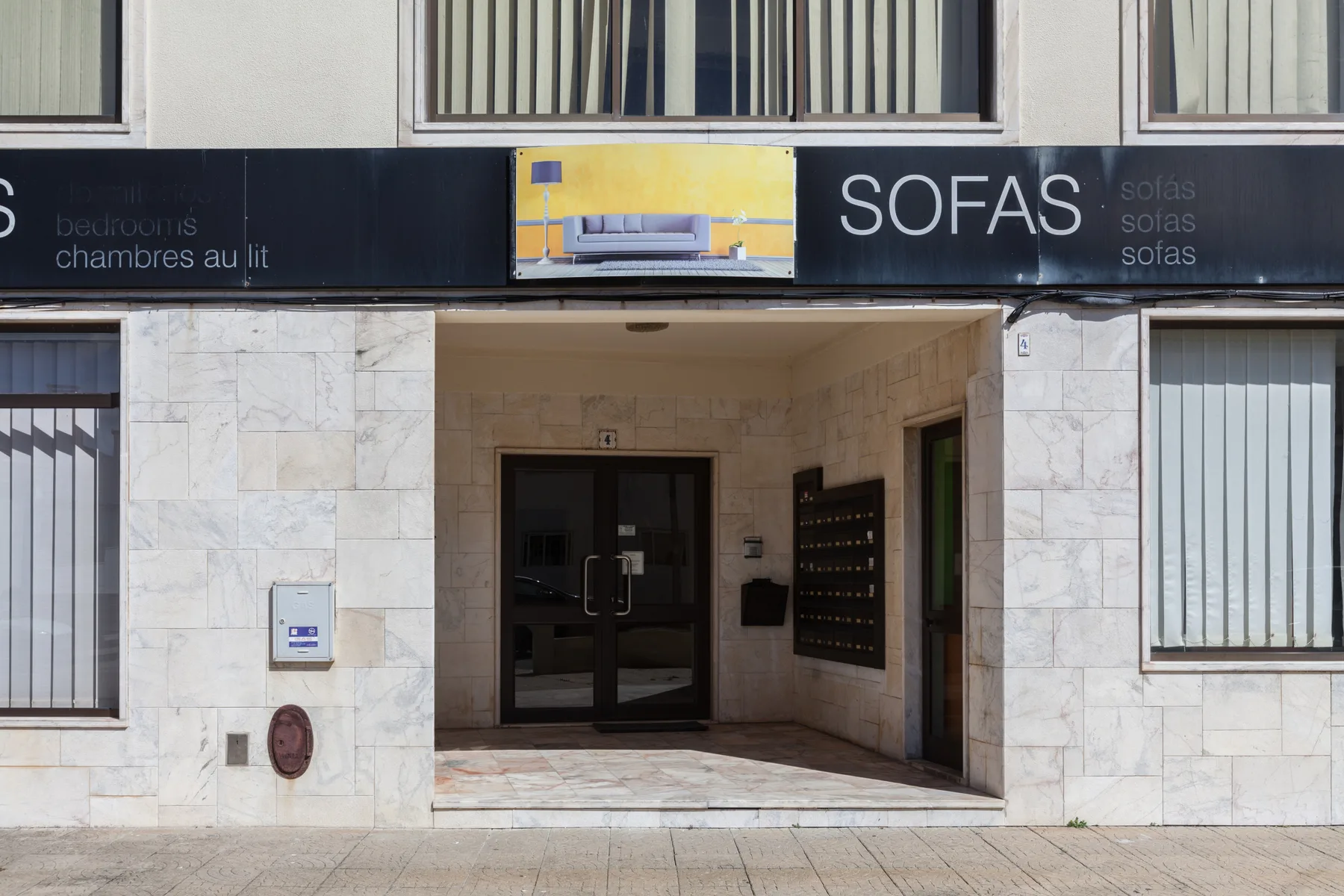 La entrada de un edificio está bajo un letrero comercial que dice «SOFAS».