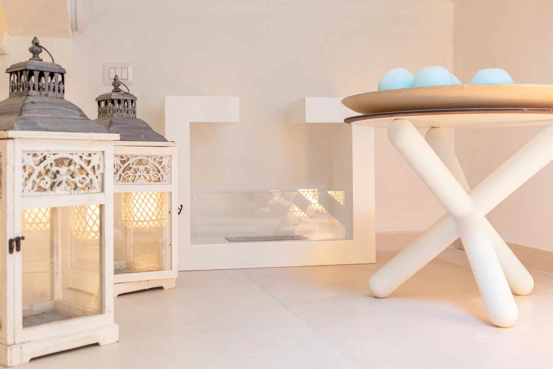 A bright interior scene with decorative lanterns beside a small round table.